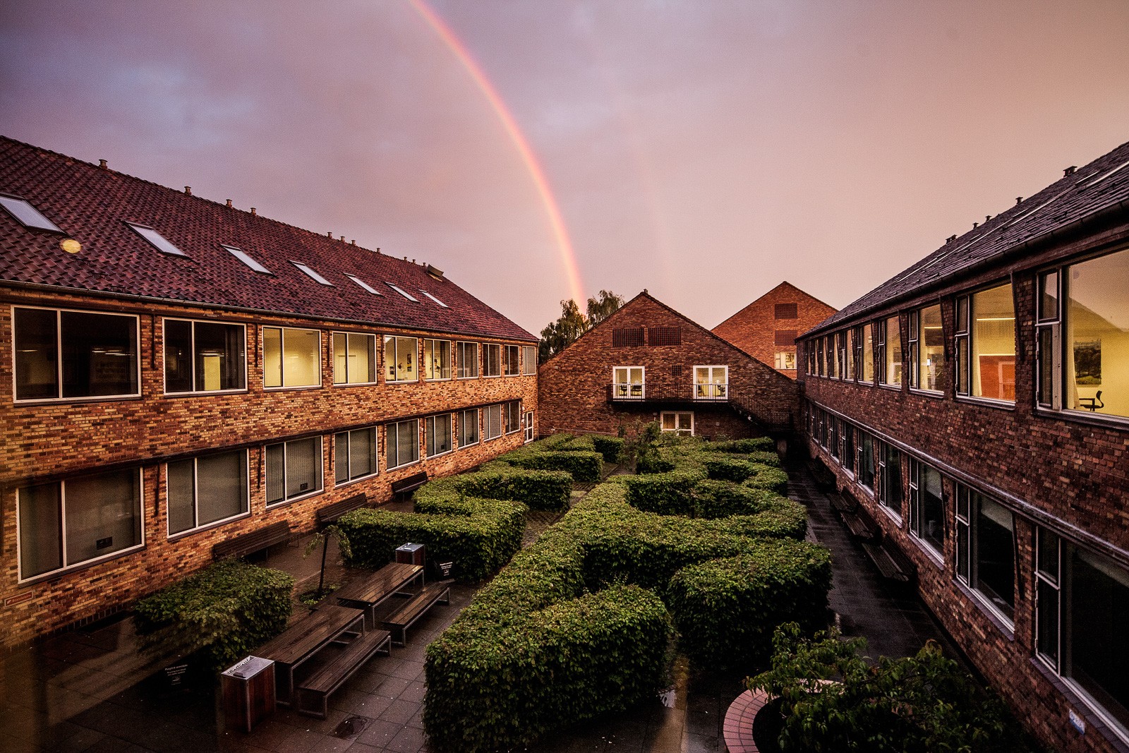 A rainbow arcs over the brick courtyard at Aarhus BSS.